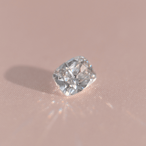 Close-up of a cushion cut diamond on a light surface, symbolising romance, comfort, and a warm sense of nostalgia.