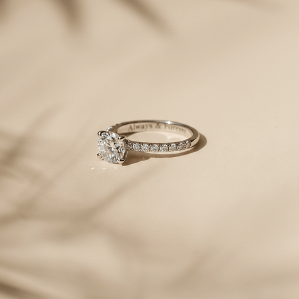 An image of a custom-made diamond solitaire engagement ring featuring an engraved detail.
