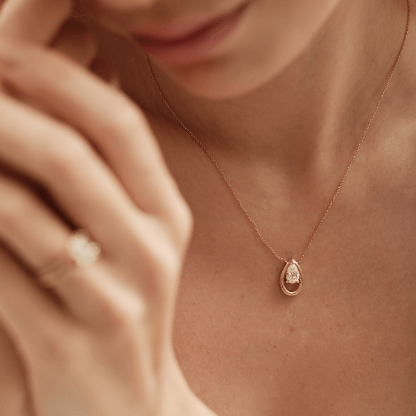 Gold pendant necklace worn at a classic length with a matching ring.