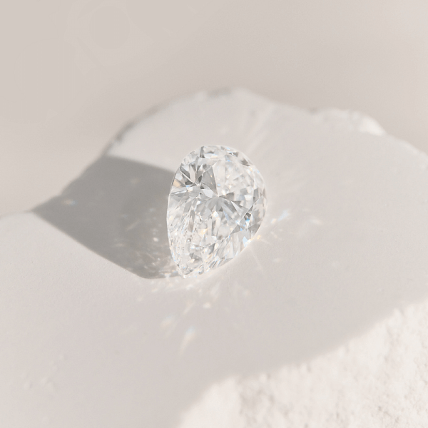Close-up of a pear shaped diamond on a light surface, symbolising elegance and individuality.