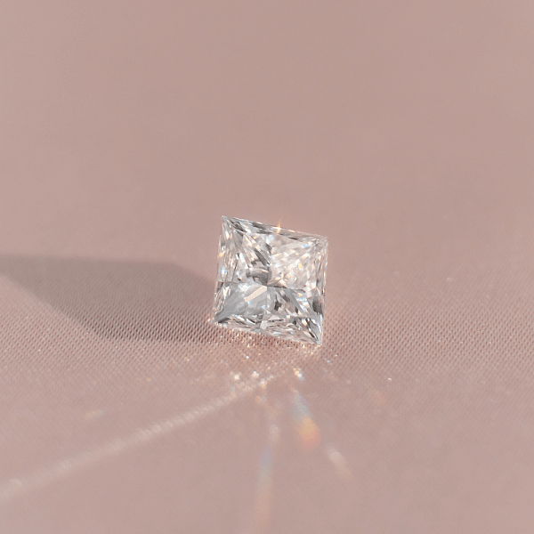 Close-up of a princess cut diamond on a light surface, symbolising boldness and a love that feels modern yet enduring.