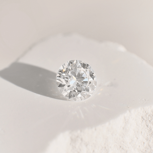 Close-up of a round brilliant cut diamond on a light surface, symbolising timeless love and classic commitment.