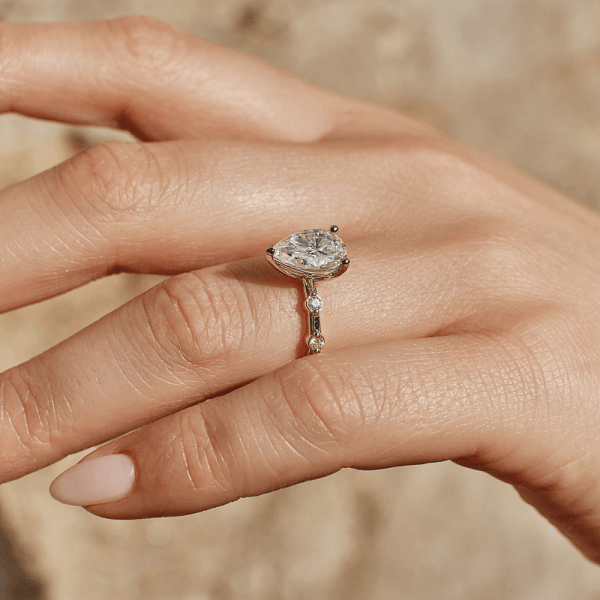 An image of a solitaire ring with a diamond, worn on a woman's hand.