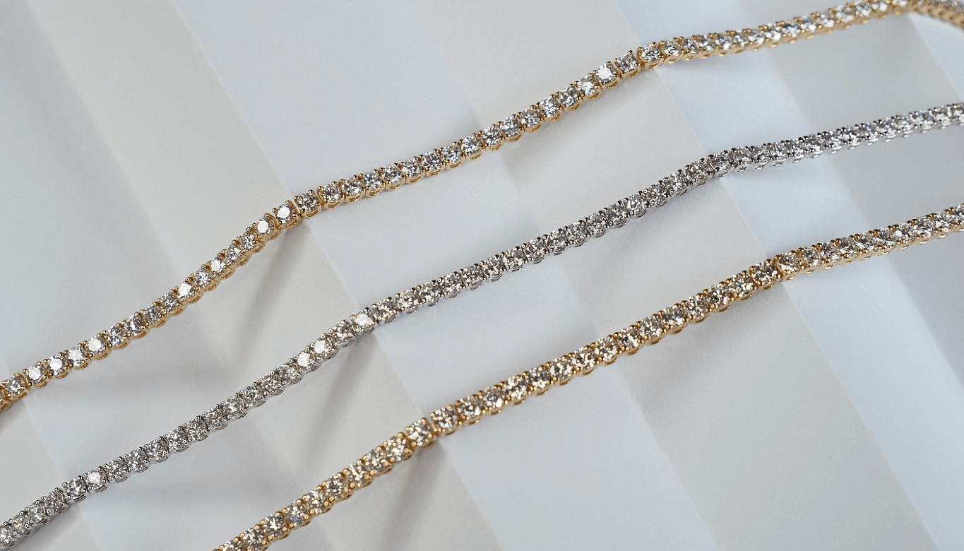 An image featuring three different diamond tennis bracelets, one in white gold and two in yellow gold.